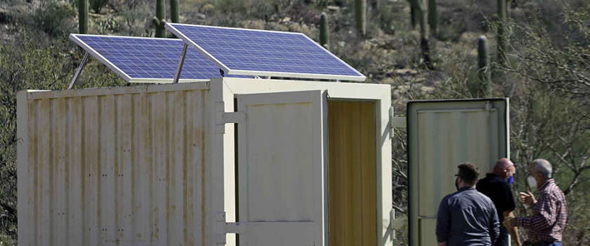The meme depicts a person using a portable toilet in a desert setting, with a solar panel on top of the toilet. The text "I'm not saying I'm a genius, I'm just saying I'm not using a battery" appears in the image, implying that the person is using the solar panel to power the toilet. The humor comes from the absurdity of using a solar panel to power a toilet in the middle of a desert.